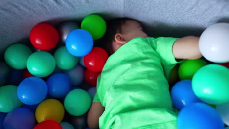happy smiling kid playing in the dry pool among the balls. top view on the child enjoying a game.