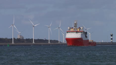 commercial ship moving up waterway with wind turbines in the background