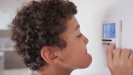 mischievous boy changes temperature on central heating thermostat control before father resets it