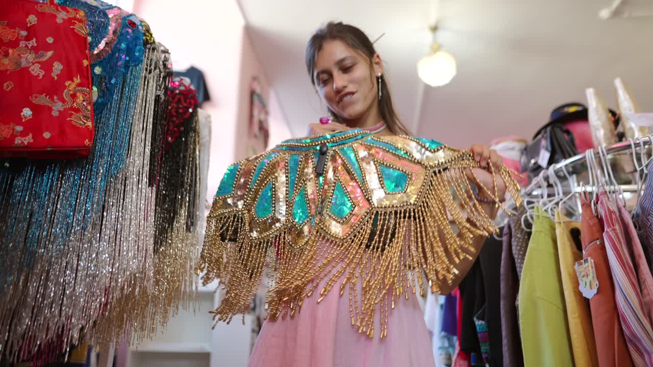 Woman shopping for vintage clothing with sequins and gold fringe