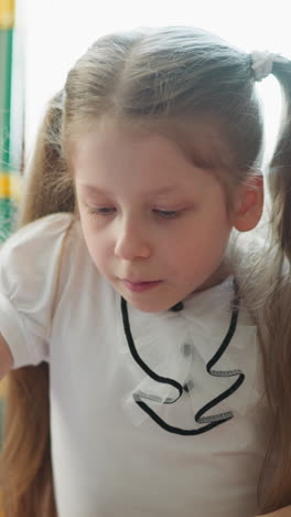 focused girl talks drawing triangle in notepad using drawing tools. schoolgirl does homework sitting in room with blackboard at home on blurred background