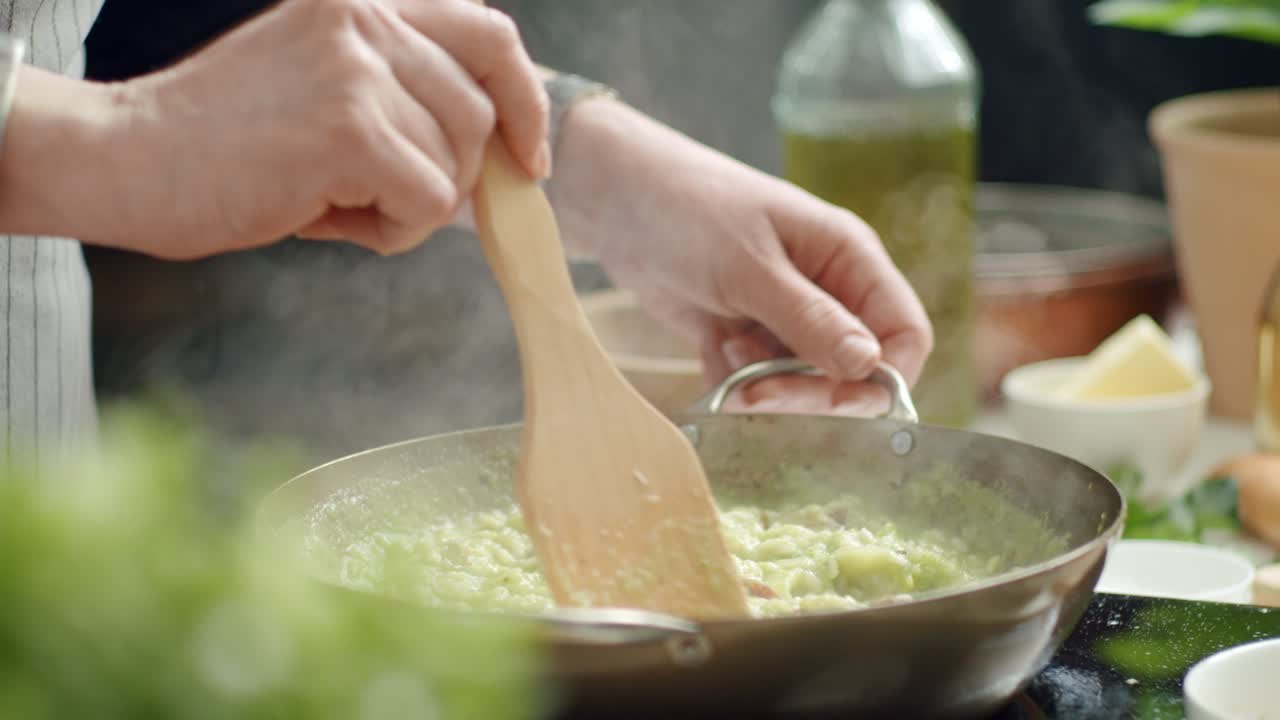 cocinero de cultivos mezclando risotto caliente en una sartén