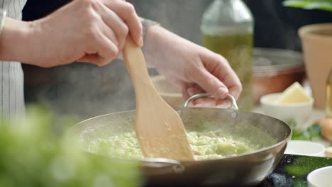 cocinero de cultivos mezclando risotto caliente en una sartén