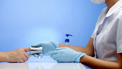 a nurse checks a patient's oxygen levels with an oximeter and gives the thumbs up signal