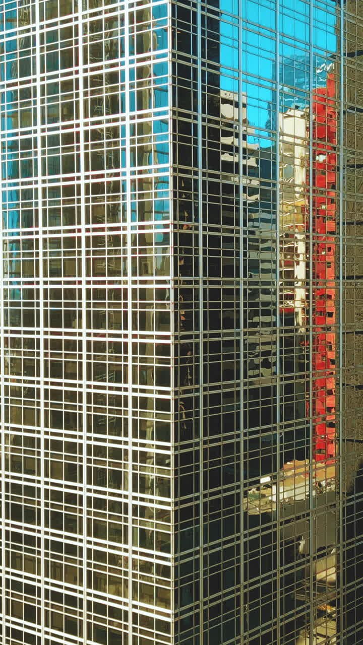 Facciata di un moderno grattacielo in vetro con riflessi di edifici cittadini