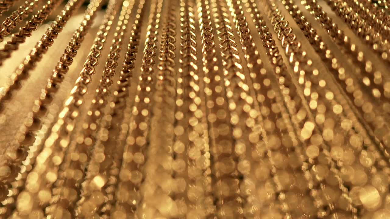 긴 금 사슬의 느리고 부드러운 움직임, 균일한 스, 휴식을 위한 금색 배경, 명상, 휴식, 진정시키기 위한 질감, 반이는 빛, 아래에서 위로 보이는 광경, 흐릿한 빛.