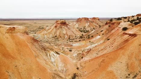 Drone-flying-up-and-backwards-in-between-beautiful-colourful-desert-hills-in-the-Australian-outback