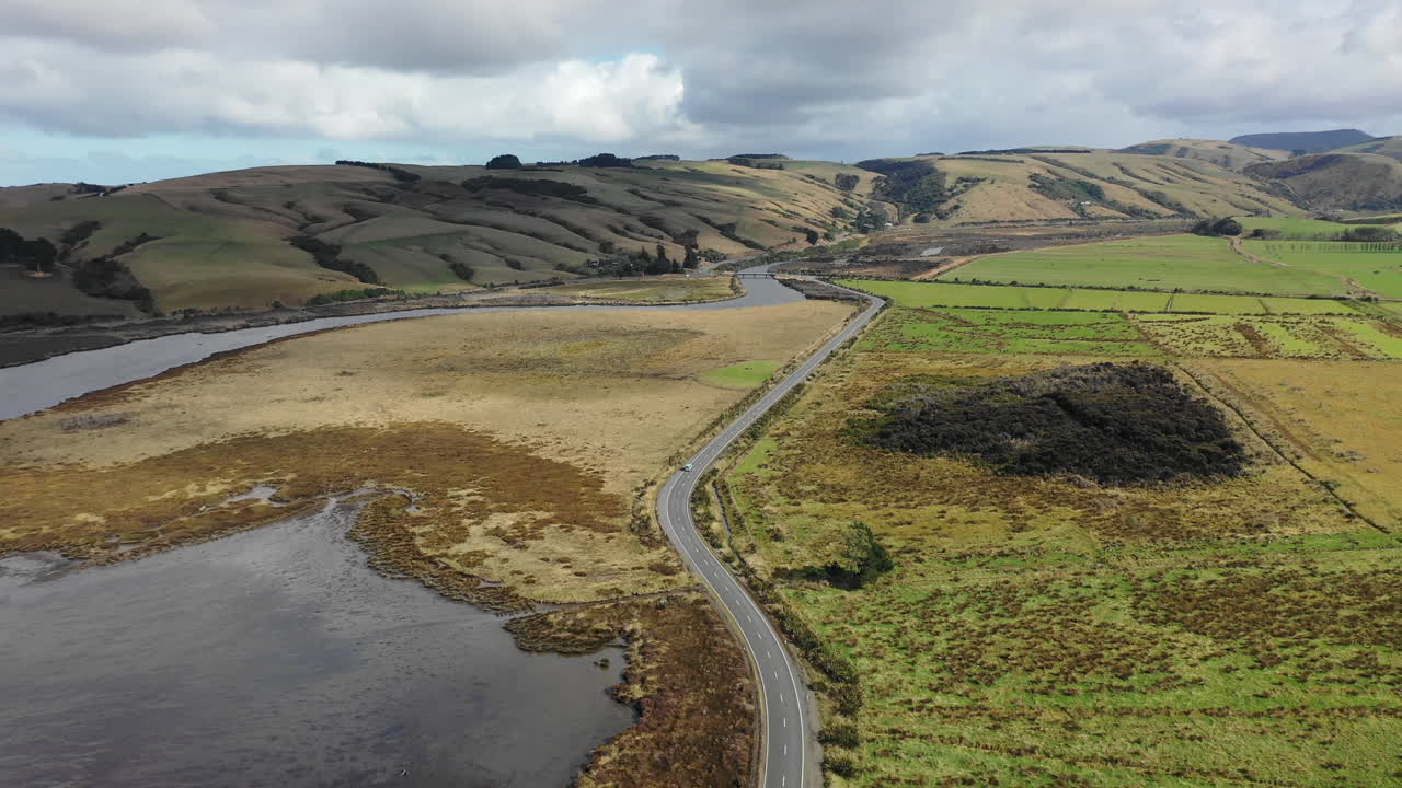 Aerial view of a car driving along a scenic road through the picturesque countryside of New Zealand's South Island