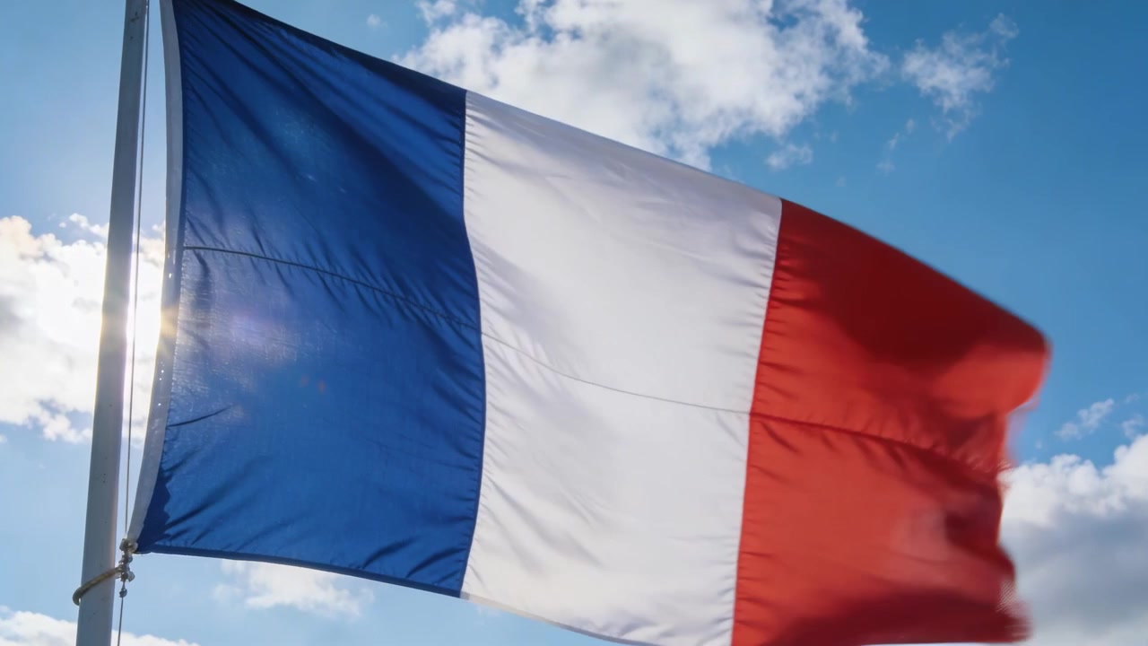 Bandiera tricolore fluttuante che ondeggia nella brezza su un'asta di metallo, cielo aperto con drizza visibile e un riflesso dell'obiettivo.