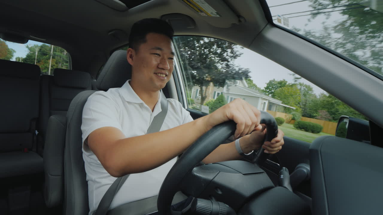 미국의 전형적인 교외 지역에서 차를 타고 웃고 있는 아시아 운전자