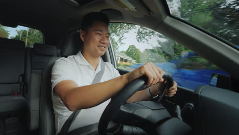 Lächelnder-Asiatischer-Fahrer-Am-Steuer-Eines-Autos-Fährt-In-Einem-Typischen-Vorort-Der-Vereinigten-Staaten