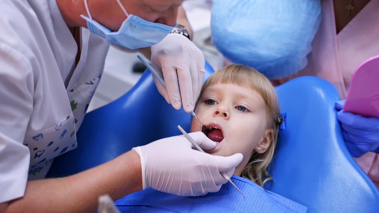 Young girl in dental surgery. Dentist performing dental procedure to girl in clinic