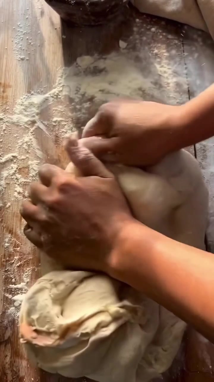 Hands Kneading Fresh Bread Dough on a Floured Wooden Surface