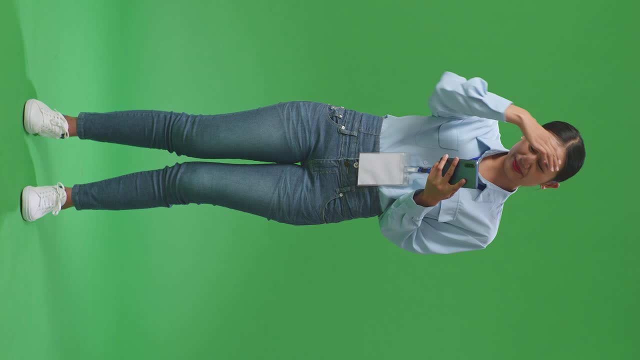 cuerpo lleno de mujer de negocios asiática no está satisfecha y sacude la cabeza mientras usa el teléfono móvil en el estudio de pantalla verde