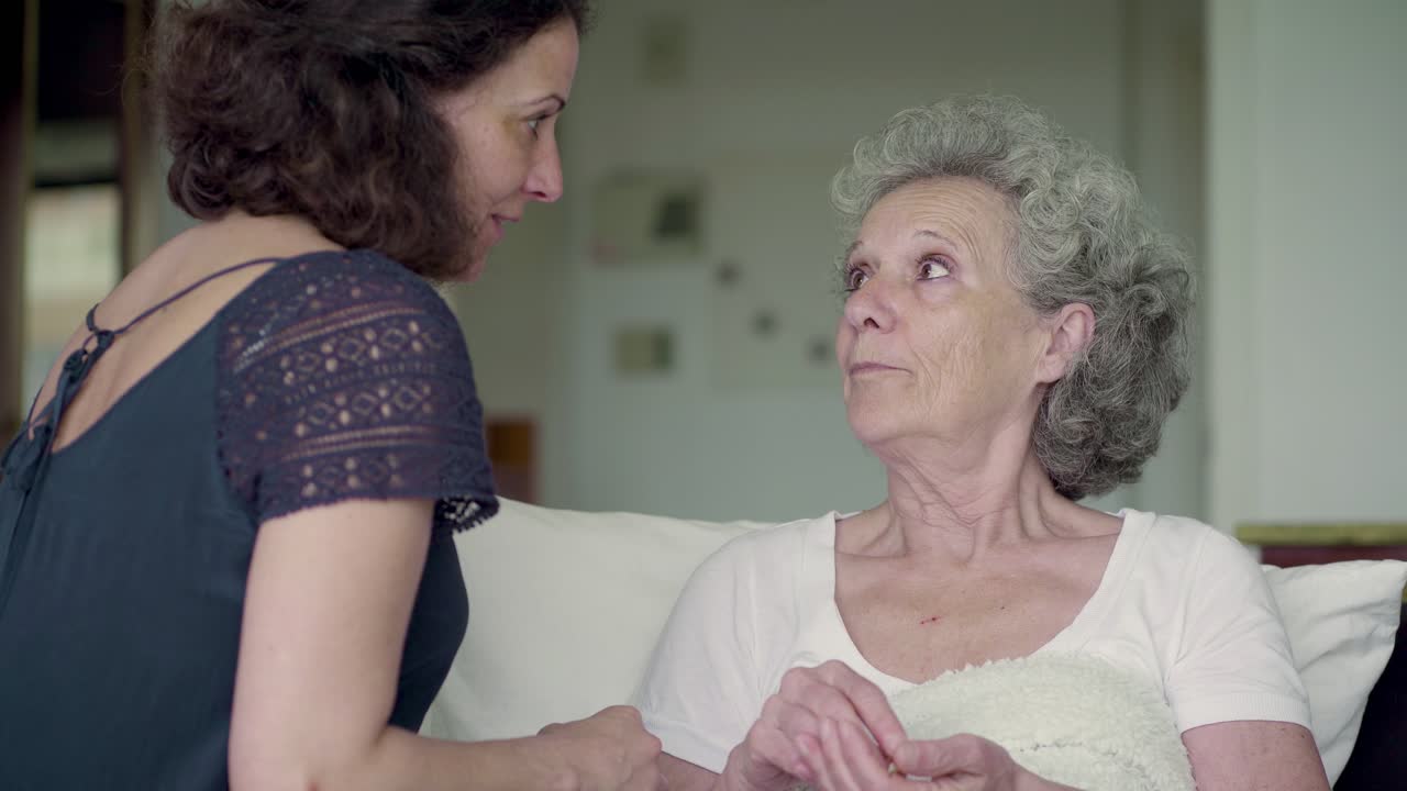 즐거운 성숙한 갈색의 여자가 고령 여성에게 약을 주고 있습니다.