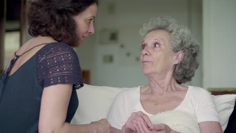 una morena madura y alegre le da pastillas a una mujer mayor.