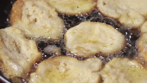 rabanadas being fried on oily hot skillet - extreme close up