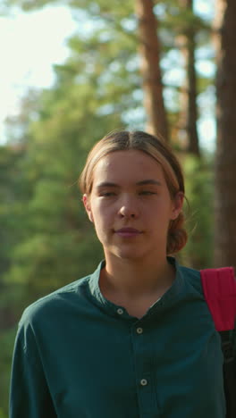 amigos caminan a través de un bosque verde exuberante, ambos con expresiones relajadas, uno lleva una corbata de cabello azul y lleva una mochila, mientras que el otro cubre una tela sobre su bolsa con su cabello atado hacia atrás