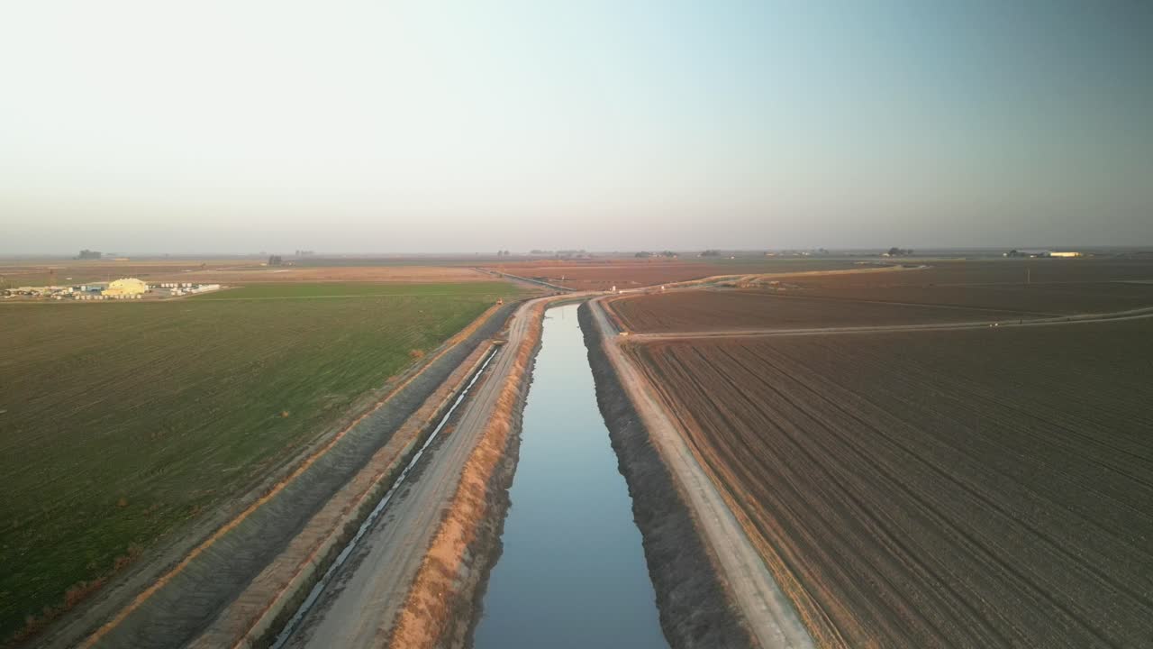 A drone descends revealing the tranquil surroundings of Lake Tulare, with lush landscapes, and neat farmland rows.