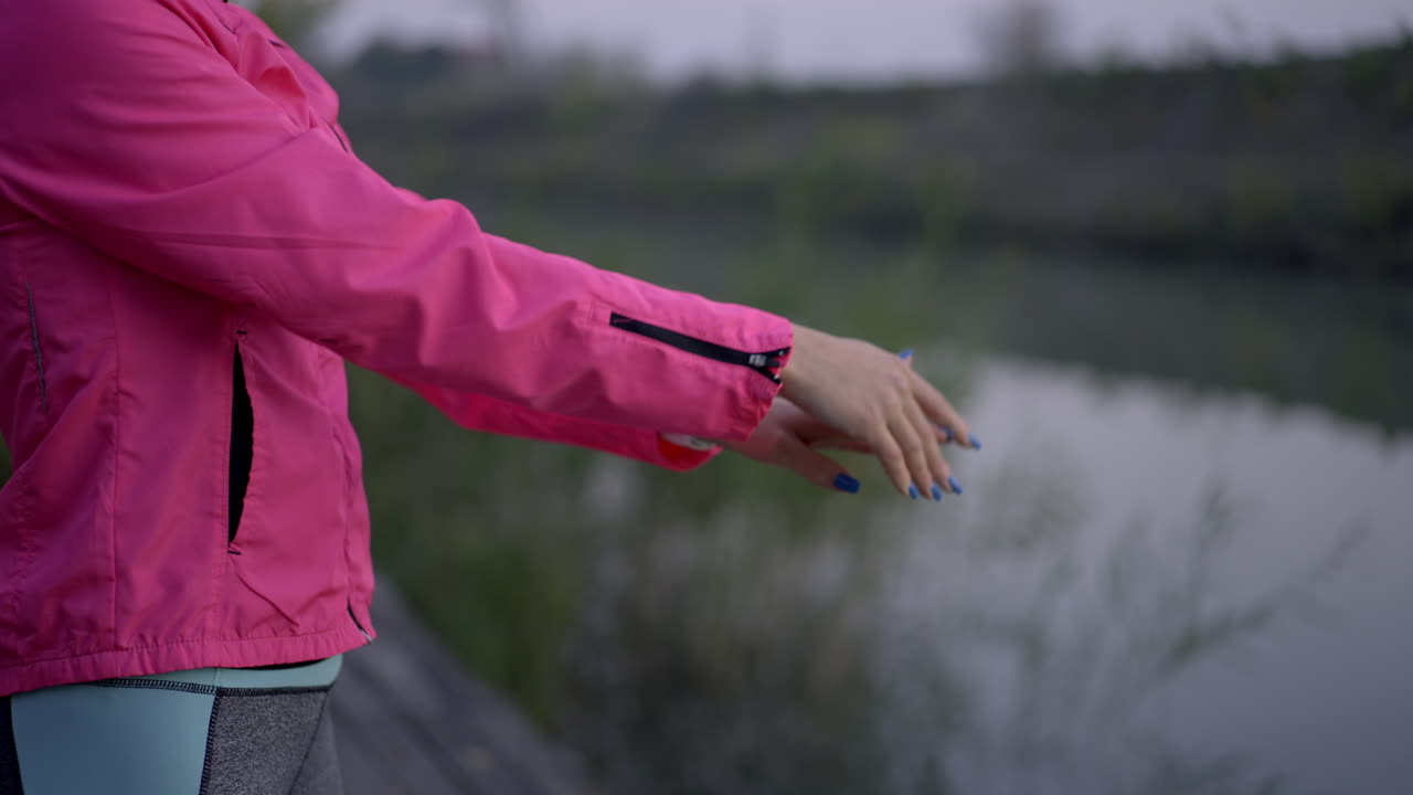 Woman Stretching Arms by a River During Outdoor Workout