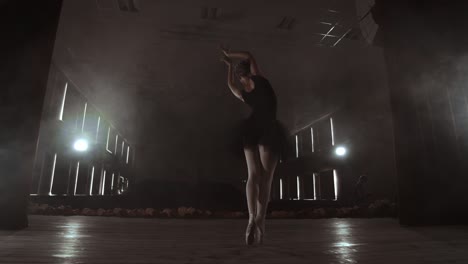 slow motion: prima ballet in a black dress performs rotations and dance graceful movements rehearsing a solo program. the camera moves on gimbal