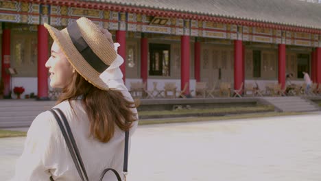 happy young backpacker woman walking  before traditional  chinese temple