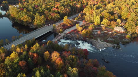 colorful autumn forest by mountain river and highway road, aerial view muskoka region of ontario, canada