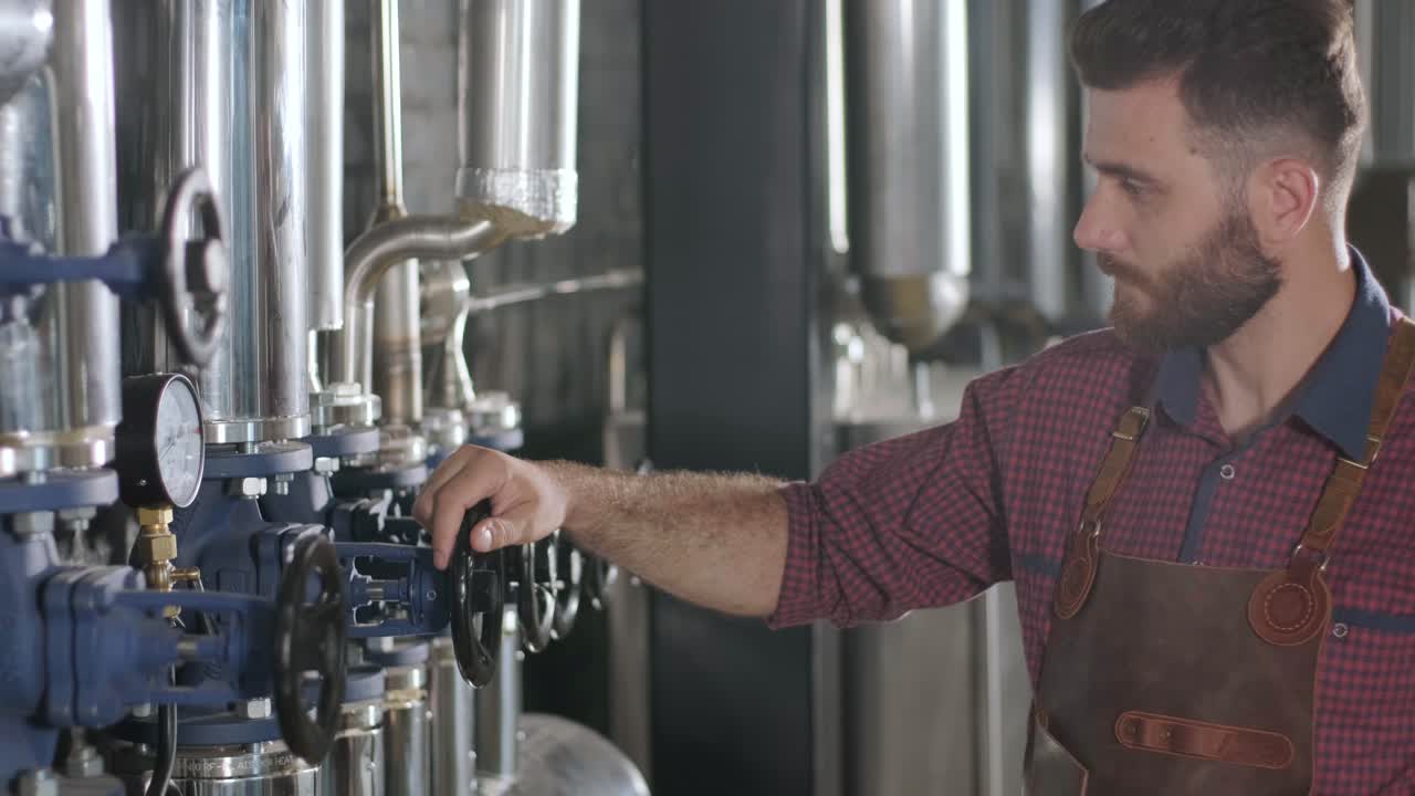 un joven cervecero con un delantal de cuero supervisa el proceso de fermentación de la cerveza en una fábrica de cerveza moderna