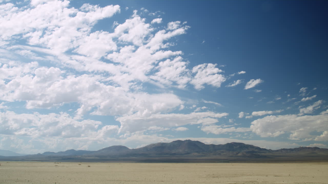 el lapso de tiempo de las nubes sobre un lecho de lago seco agrietado en el desierto de nevada de verano caliente