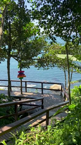 Tropical-ocean-view-through-lush-green-trees-with-colorful-signposts