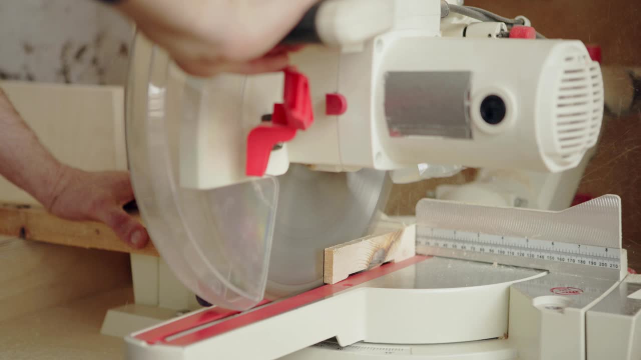 나무판의 작은 조각을 잘라내기 위해 원형 도자기를 사용하는 아프론을 입은 인식할 수 없는 목수의 손