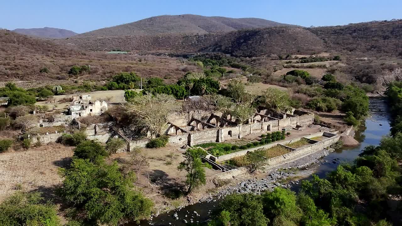 Aerial: Ex Hacienda de San Jacinto Ixtoluca, landscape view with rock wall and blue sky during the day in La Mezquitera, Morelos, Mexico, pan drone shot