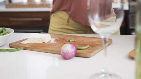 midsection of senior african american woman cooking, preparing vegetables, copy space, slow motion