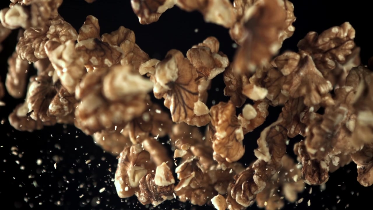 Shelled Walnuts Falling in Slow Motion Against a Black Background