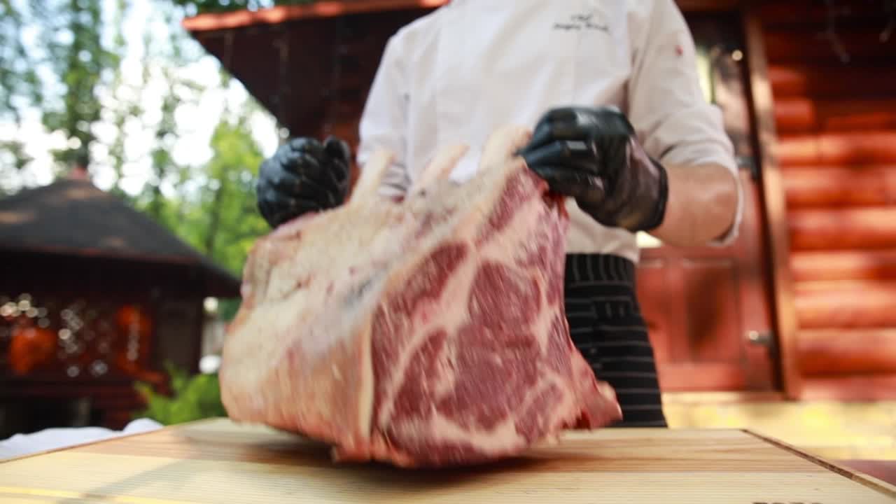 Chef preparing a raw rib eye steak outdoors