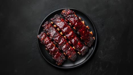 deliciosas costillas de barbacoa en un plato negro con salsa