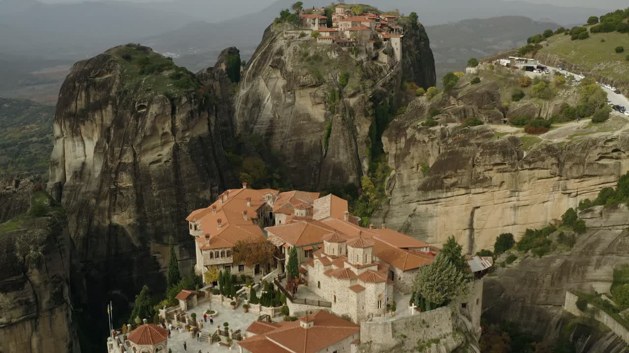 vista aérea lejos del gran monasterio de meteoritos y sobre el claustro de varlaám en meteora, grecia - reversa, inclinación, disparo de drones