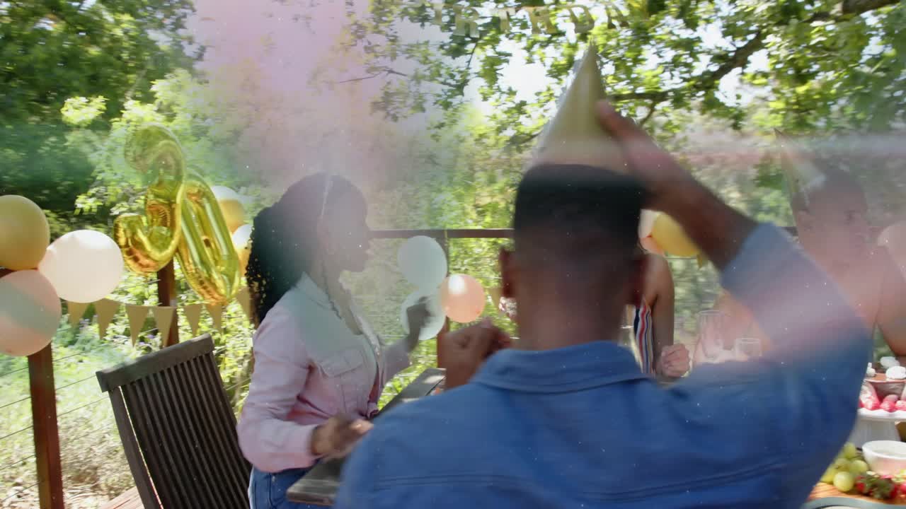 Woman in pink handing gift, friends opening and donning hats, toasting birthday under 30 balloon