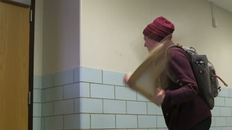estudiante universitaria rompe la pintura contra la pared con enojo