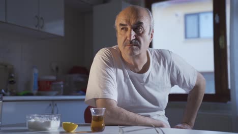 Sad-depressed-mature-old-man-sitting-alone-in-the-kitchen-room-and-thinking.