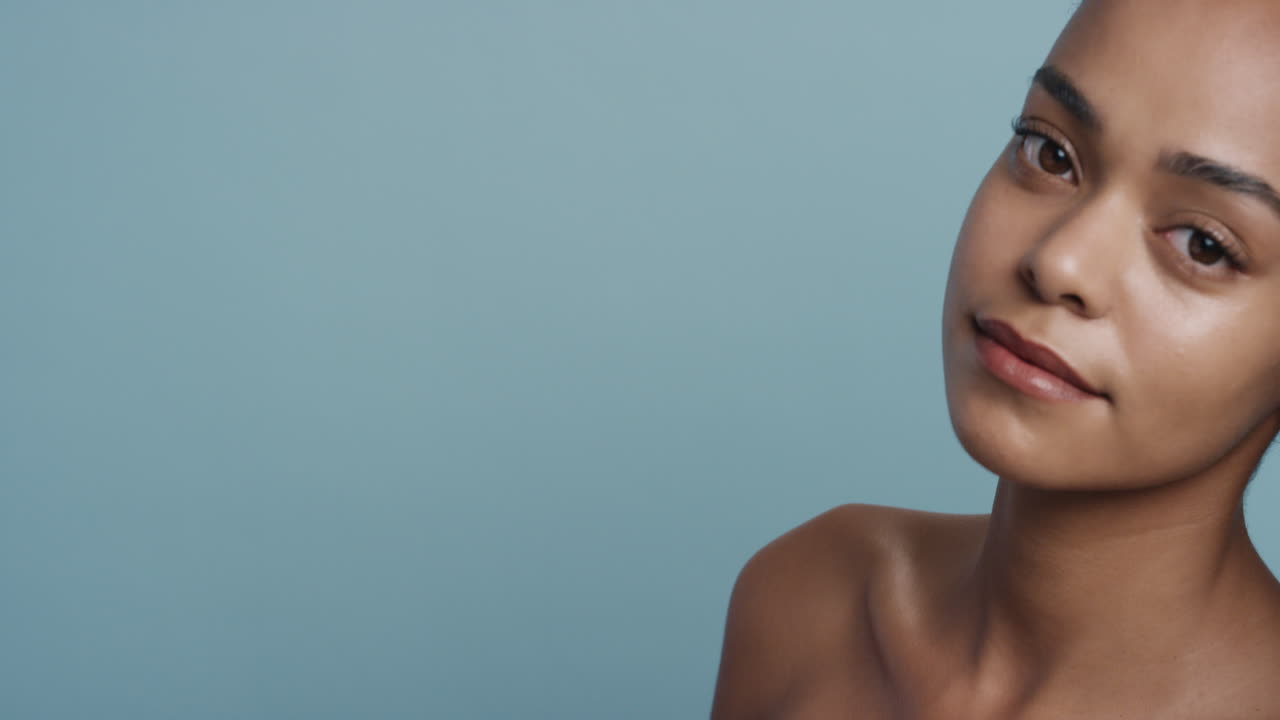 ritratto bella giovane donna afroamericana con pelle liscia e sana che sembra sensuale attraente donna che gode di una sana cura della pelle bellezza su sfondo blu spazio di copia