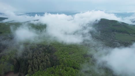 órbita aérea sobre nubes blancas bajas y esponjosas y montañas bajas de bosque verde tatra en banska bystrica, atmósfera tranquila del paisaje eslovaco