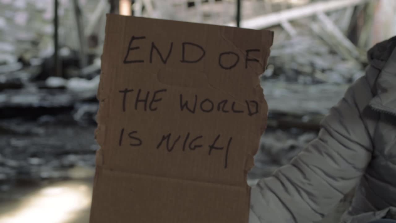 Arm holding sign warning of the end of world in rubble background