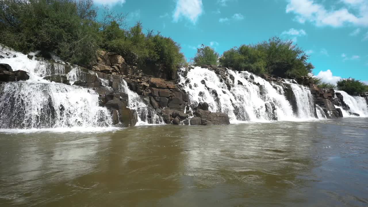 vista baja de seguimiento sobre el agua en las cascadas de mocona con cielo azul, brasil