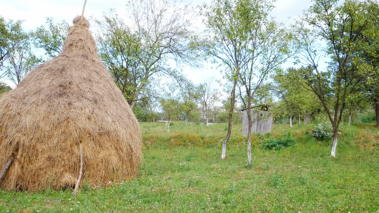 toma panorámica de un montón de paja y un viejo retrete de madera en una zona rural