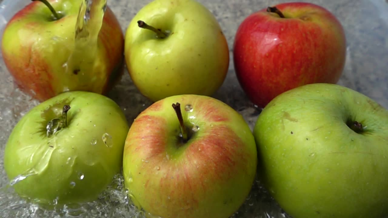 Omenoiden pesu vesisuihkun alla. Hidastettu kuva.