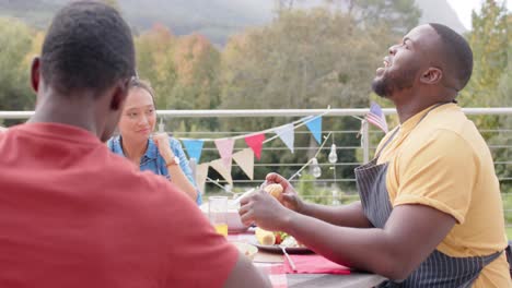 Happy-diverse-group-of-friends-eating-and-talking-at-dinner-table-in-garden,-slow-motion