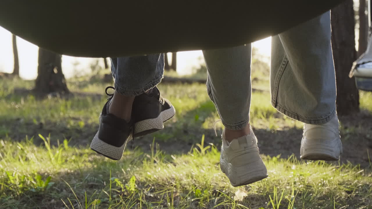 숲 한가운데 해먹에서 흔들리는 두 소녀의 발