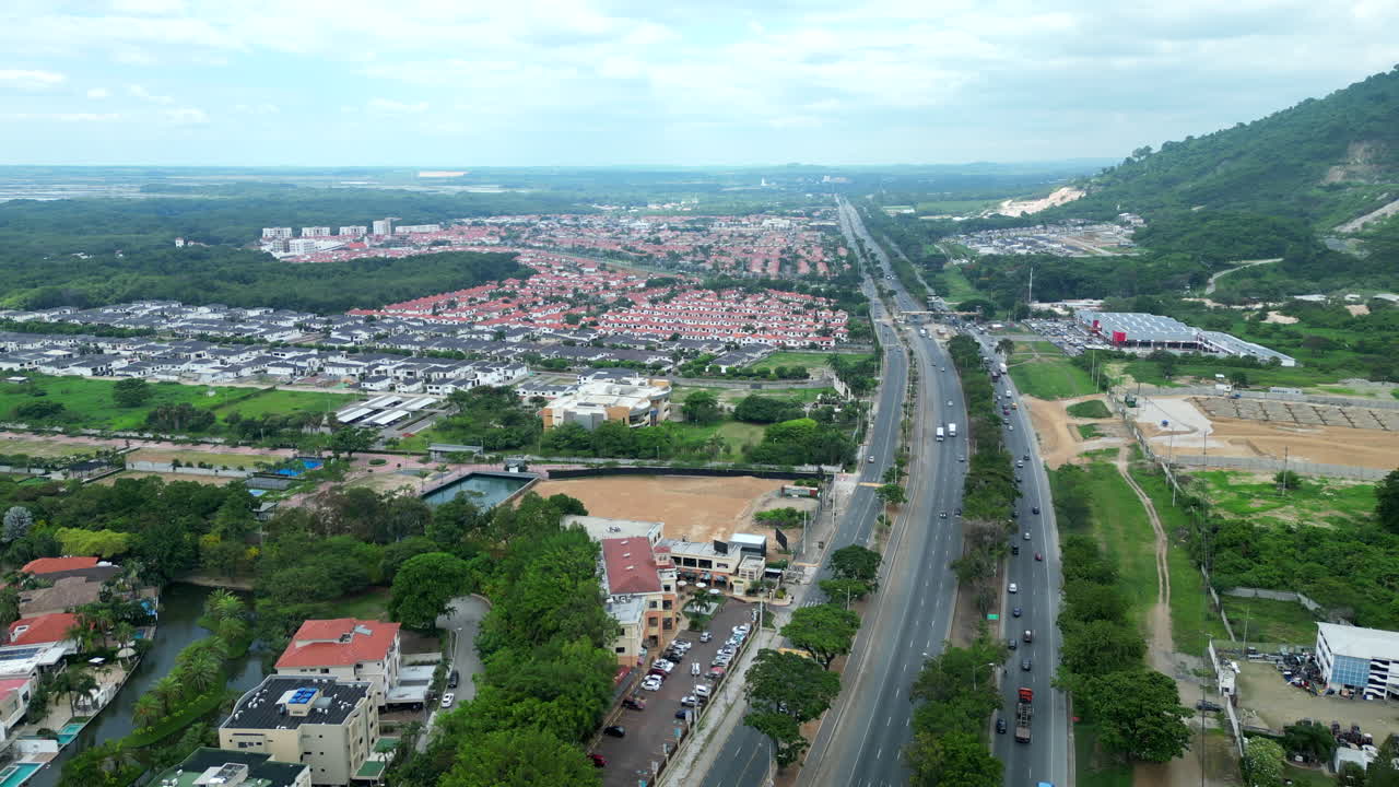 Aerial footage of Via a la Costa, Ecuador. Showcases the highway, residential areas, and lush landscapes. Perfect for travel, real estate, and urban planning visuals.