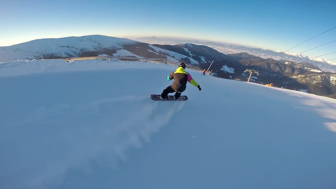 Back view of a high speed snowboarder with amazing tatra mountain view at sunset. 60 fps, Jasna, Slovakia.